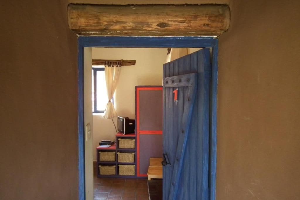 A doorway leading to a room with a television, shelves, and baskets.