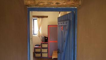A doorway leading to a room with a television, shelves, and baskets.
