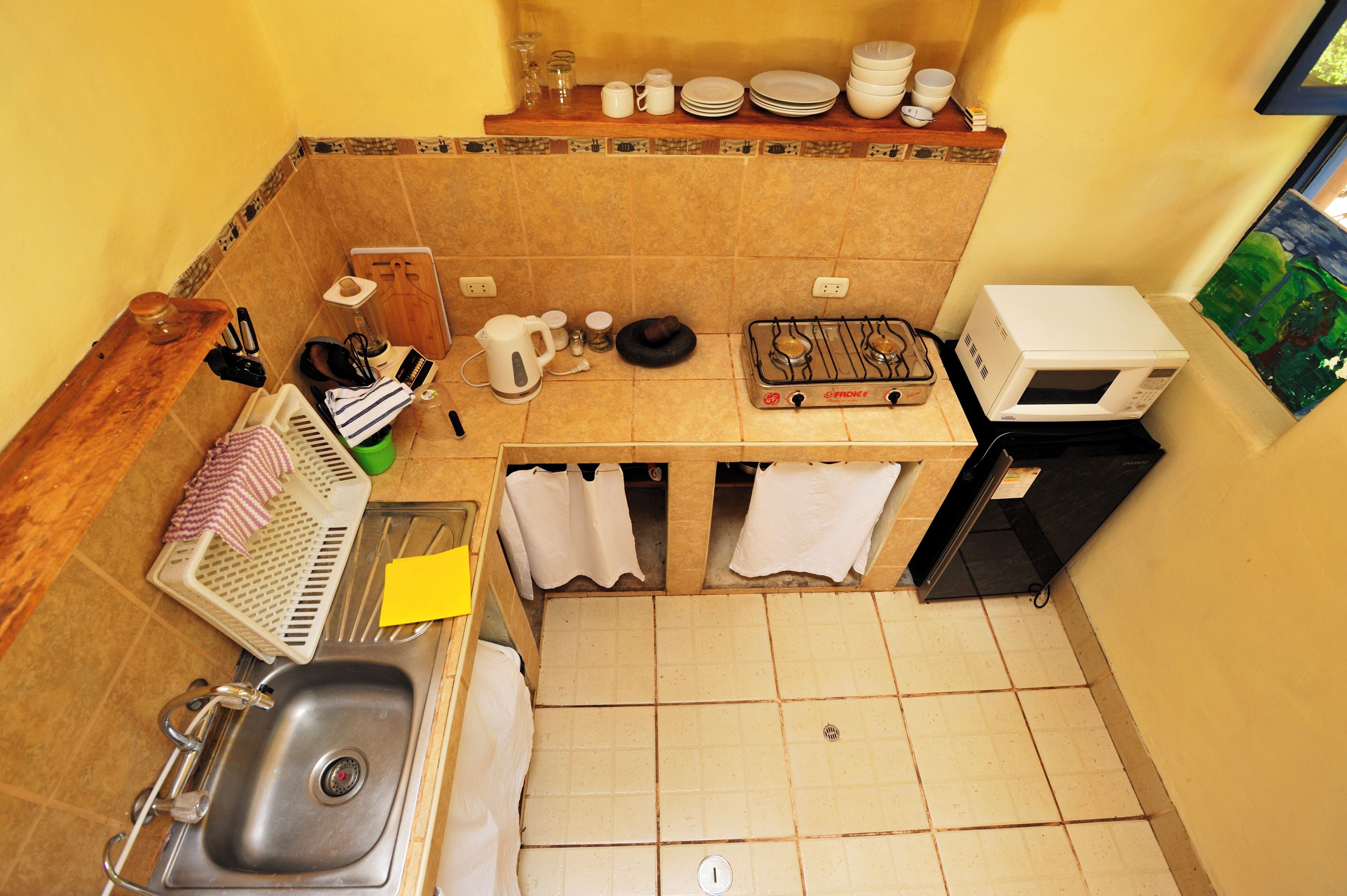 Cuina compacta amb rentamics, fogó, forn de microones i diferents utensilis de cuina.