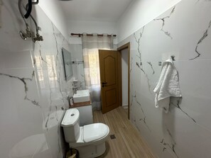 A bathroom with a toilet, sink, and shower area.