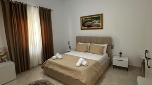 Quarto com cama, mesa de cabeceira, tapete e uma pintura na parede.