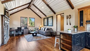 A spacious living area with a high ceiling, wooden beams, a sofa, a coffee table, and a kitchen area with cabinets and a countertop. - The Water Tower House by Avantstay Tower Card Room + Casita + Game Room Panoramic Cascade Views (Powell Butte)