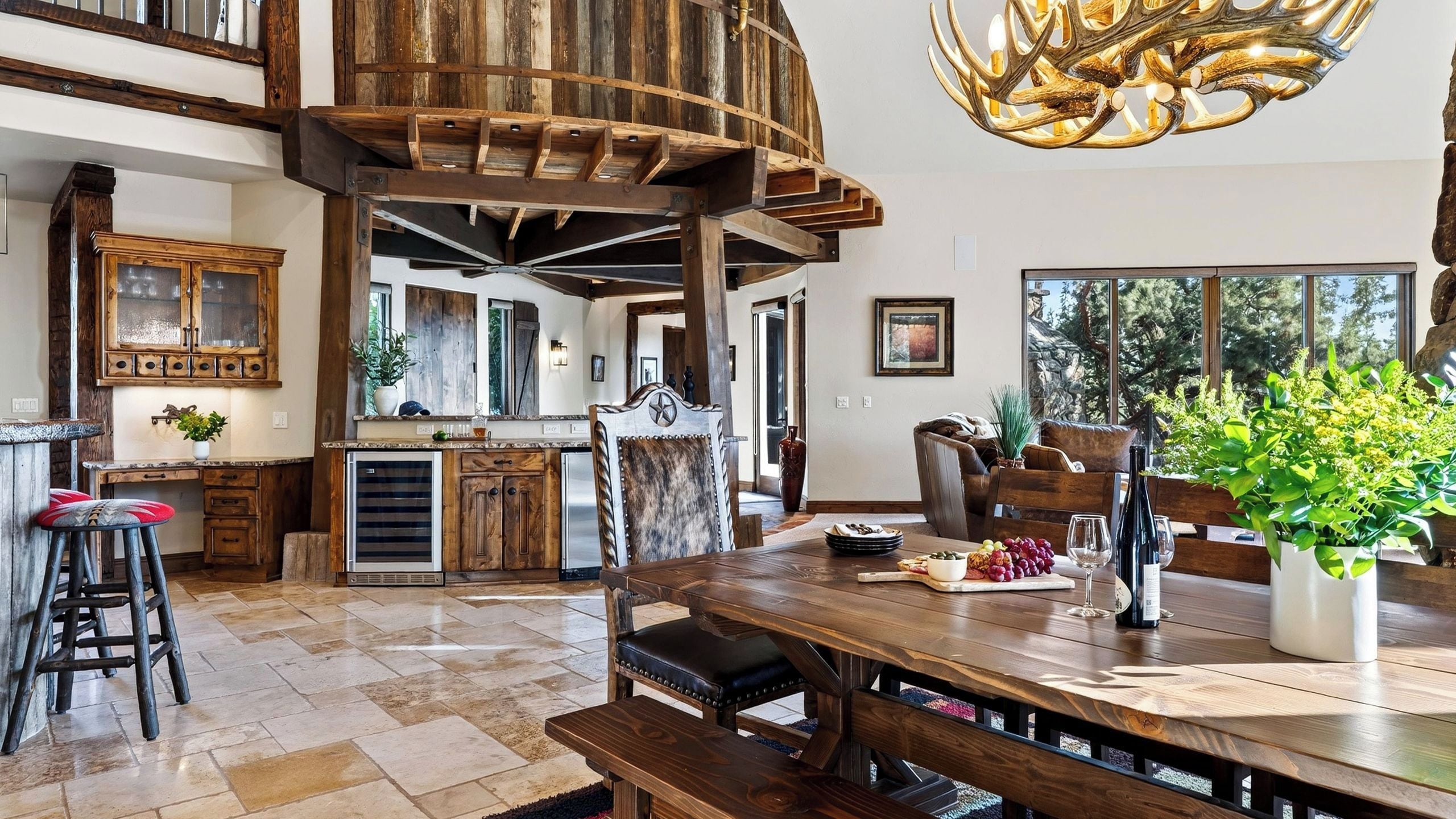 A spacious kitchen with a high ceiling, rustic wooden beams, and a large dining table set for a meal.