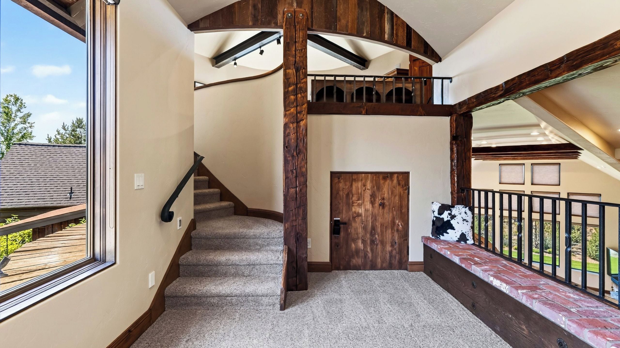 A staircase with a wooden handrail, carpeted steps, and a door leading to an outdoor area.