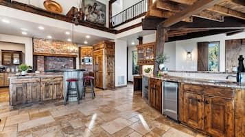 A spacious kitchen with a large island, wooden cabinetry, and a stone backsplash.