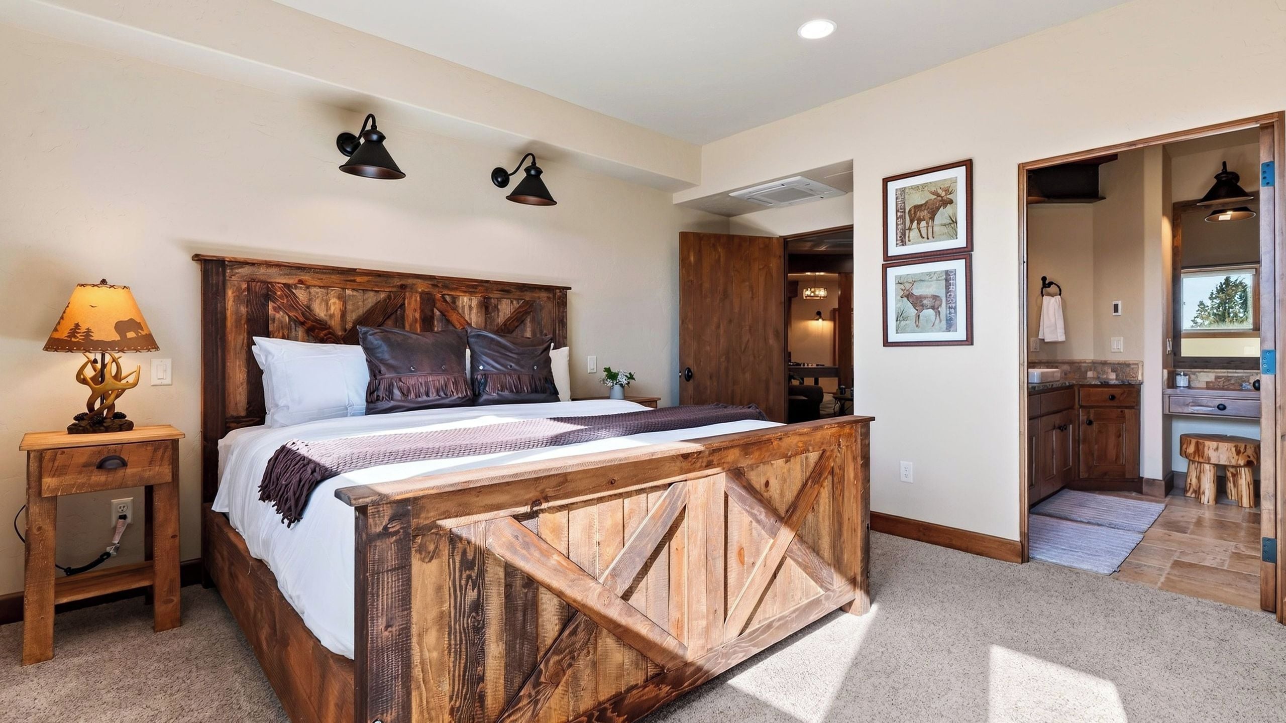 Un dormitorio con cabecera de madera, una mesita de noche con lámpara y una cama con almohadas.