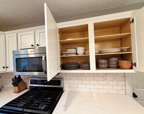 A kitchen with white cabinets, a stainless steel oven, a microwave, and a stove. - The River House (Bismarck)