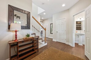 A hallway with a wooden console table, a mirror, and a red lamp. - Loon Basecamp - Townhome Near Loon Mtn, Sleeps 12, Pools, Hot Tub, Game Room (Lincoln)