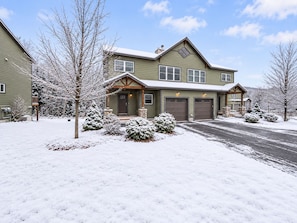 A two-story house with a garage, a front porch, and snow-covered surroundings. - Loon Basecamp - Townhome Near Loon Mtn, Sleeps 12, Pools, Hot Tub, Game Room (Lincoln)