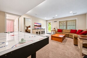Een kamer met een tafelvoetbal tafel, een bank, een bijzettafeltje en een televisie.
