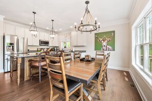 A spacious kitchen with modern appliances, a large dining table, and a chandelier. - Loon Basecamp - Townhome Near Loon Mtn, Sleeps 12, Pools, Hot Tub, Game Room (Lincoln)
