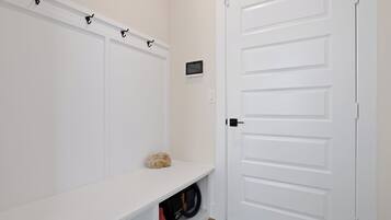 Eine weiße Tür mit schlichtem Design, eine kleine Ablage mit einem Stein und einem roten Gegenstand, sowie ein an der Wand befestigtes Gerät.