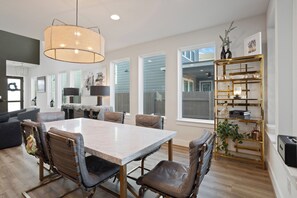 A modern kitchen with a marble countertop, a dining area with a white table and leather chairs, and a decorative gold shelf with glassware. - 3 BDRM East Austin Home - Mins to Downtown (Austin)