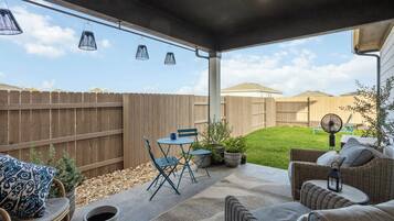 Eine Terrasse im Freien mit überdachtem Sitzbereich, einem Holzzaun und einem Rasen.
