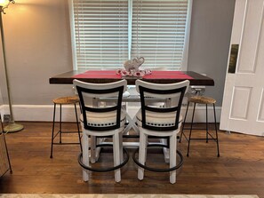 A dining area with a table, two chairs, a red placemat, and a window with blinds. - 1 mile to Bryant Denny Stadium (Tuscaloosa)