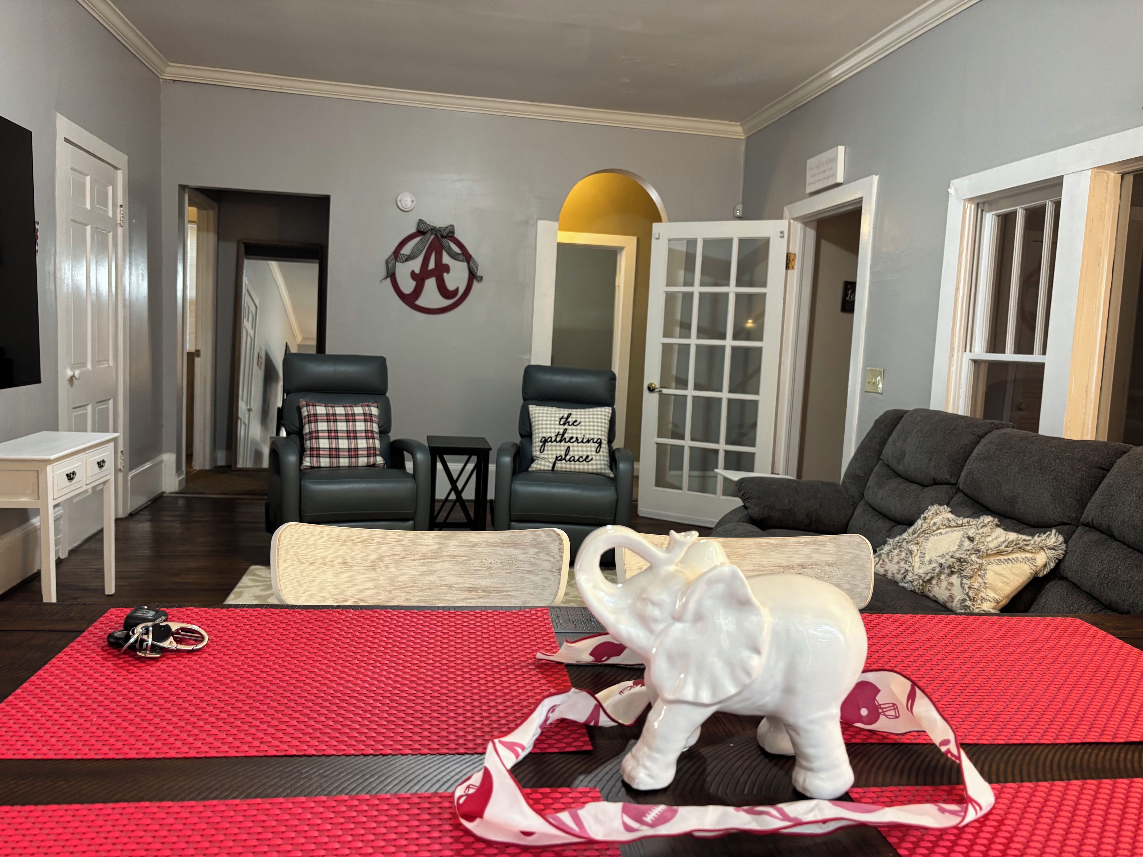 Een woonkamer met een hoekbank, twee fauteuils, een salontafel en een decoratief olifantje op een rode mat.