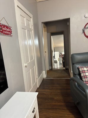 Ein Flur mit einer weißen Tür, einem schwarzen Ledersofa und einem roten und weißen Schild an der Wand.
