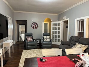 Ein Wohnzimmer mit einer Couch, zwei Sesseln, einem Couchtisch und einem Fernseher.
