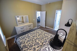 A bedroom with a bed, dresser, and a door leading to another room. - 1 mile to Bryant Denny Stadium (Tuscaloosa)