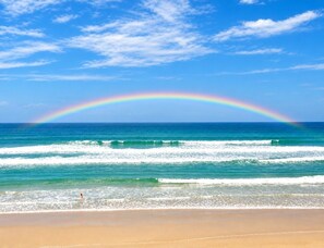 Ein Strand mit Wellen und einem Regenbogen.