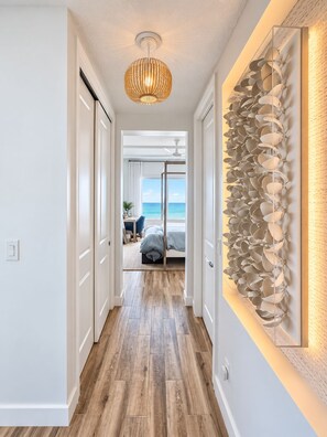 A hallway with a wooden floor leading to a bedroom with a view of the ocean. - TYDEMARK LUXURY☆ Oceanfront 
2 King Suites • Heated Pool•Walk 2 Flagler•DEC-MAR (New Smyrna Beach)