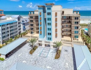Ein mehrstöckiges Hotel mit Balkonen, einem Poolbereich und Blick auf den Strand.