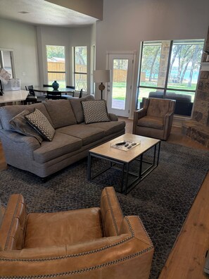 A living room with a sectional sofa, leather armchairs, a coffee table, and a dining area with a table and chairs. - Lovely spacious Lake house on Eagle Mountain Lake in charming Fort Worth (Fort Worth)