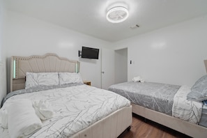 A bedroom with two beds, a ceiling fan, a mounted TV, and a door. - Bellaire Spacious 4 Br Home - sleep comfortably for 12 people + (Houston)