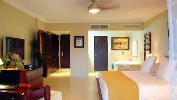 Habitación de hotel con cama, escritorio, silla y baño con lavamanos y espejo.