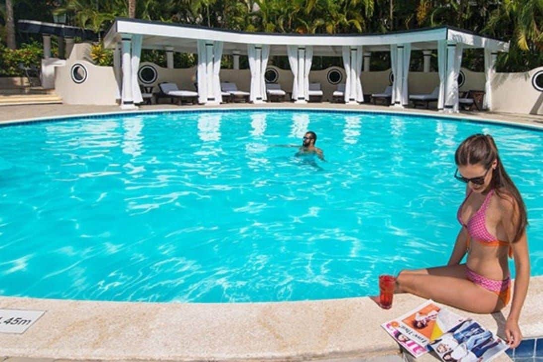 Piscina com espreguiçadeiras e área de estar coberta.
