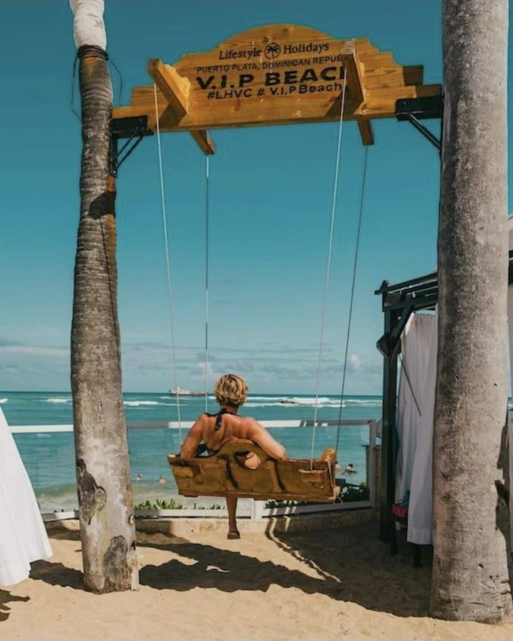 Uma cadeira de balanço de madeira em um local à beira-mar, com uma placa em cima.