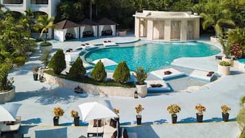 A resort with a large pool, lounge areas, and a covered seating area.
