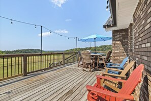 A wooden deck with outdoor furniture, a table, and chairs, overlooking a grassy field. - 12-Acre Nashville Retreat - Sleeps 12 - Game Room (Goodlettsville)