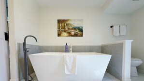 Uma casa de banho moderna com banheira independente, chuveiro e sanita.
