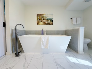 Een moderne badkamer met een vrijstaand bad, een douche en een toilet.