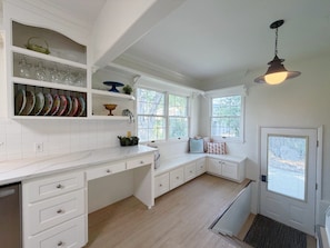 A kitchen with white cabinetry, a built-in window seat, and a hanging light fixture.