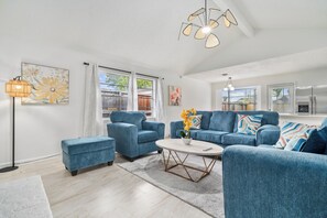 A modern living room with a blue sofa set, a coffee table, and a floor lamp. - Asiantown Escape - Cozy 3br Bellaire Home W Game Room (Houston)