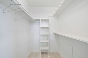 Ein weißer Schrank mit Regalen und Kleiderstange.