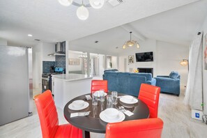 A modern kitchen with a built-in stove, a dining area with a round table and red chairs, and a living area with a blue sofa. - Asiantown Escape - Cozy 3br Bellaire Home W Game Room (Houston)