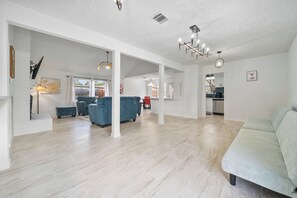 A spacious living area with a light-colored floor, a blue sofa set, and a light green couch. - Asiantown Escape - Cozy 3br Bellaire Home W Game Room (Houston)
