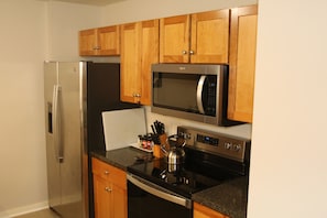 A kitchen with wooden cabinets, a stainless steel refrigerator, a microwave, and an oven. - Townhouse in Athens City with 5 beds, 3 bedrooms, 2.5 baths, garage, Wi-Fi (Athens)