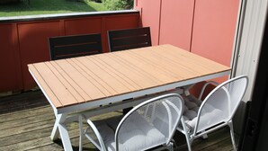 Uma mesa de madeira com cadeiras em um deck.