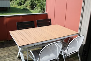 Ein Holztisch mit Stühlen auf einer Terrasse.