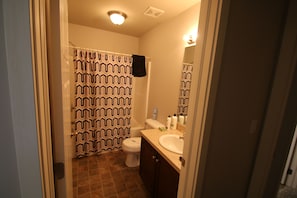 Ein Badezimmer mit Duschvorhang, Toilette, Waschbecken und Spiegel.