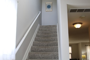 A staircase with a patterned carpet, white walls, a ceiling light, and a framed picture on the wall. - Townhouse in Athens City with 5 beds, 3 bedrooms, 2.5 baths, garage, Wi-Fi (Athens)