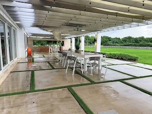Un patio exterior con zona de estar cubierta, una mesa y sillas.