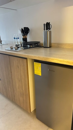 Una cocina con lavavajillas de acero inoxidable, estufa a gas y un portalapices para cuchillos en la encimera.