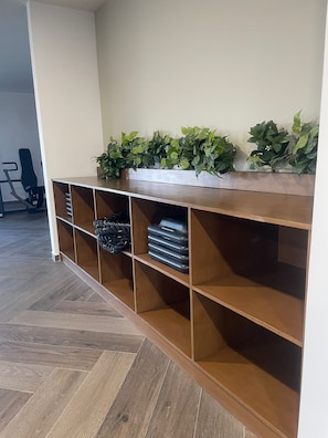 A wooden console with multiple shelves, some containing black objects and others empty. - Suite King en el Centro Guadalajara (Guadalajara)