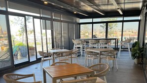 A spacious indoor area with multiple tables and chairs, large windows offering views of the city, and a modern ceiling design. - Suite King en el Centro Guadalajara (Guadalajara)