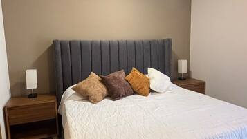 A bedroom with a bed, a ceiling fan, and a nightstand with a lamp.
